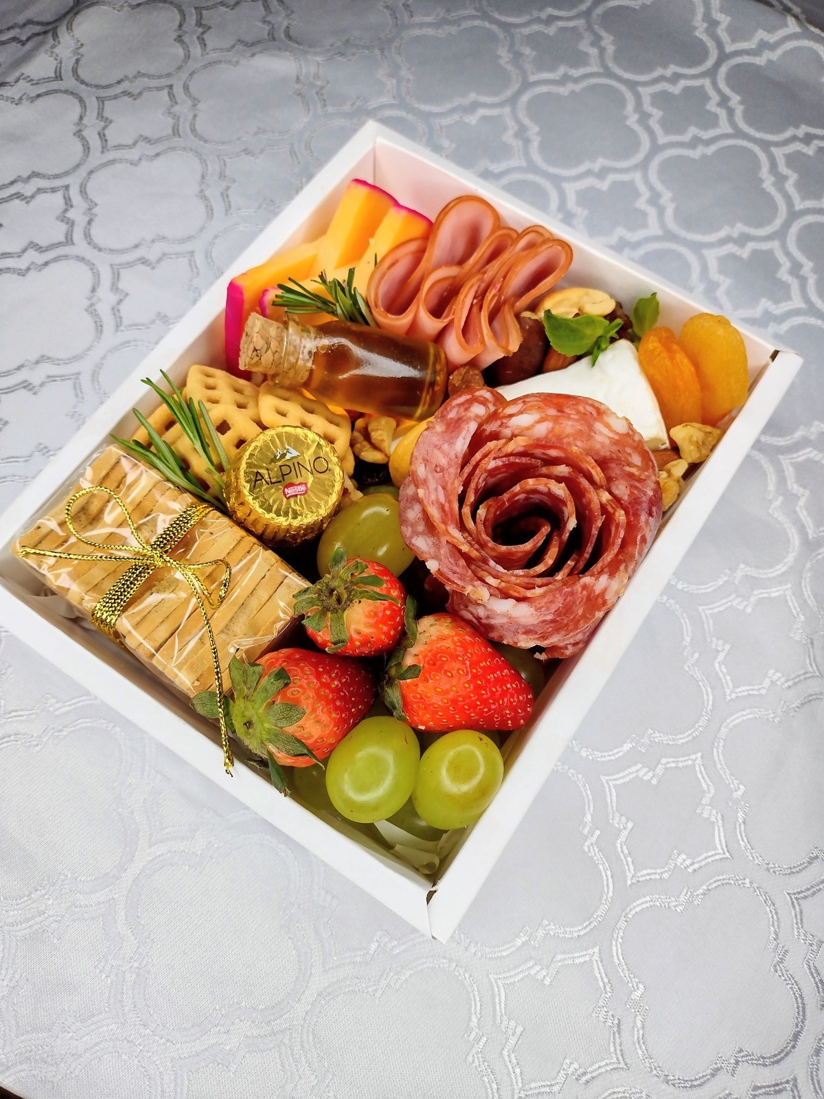 Box de frios com rosa de salame, morangos, uvas e queijos