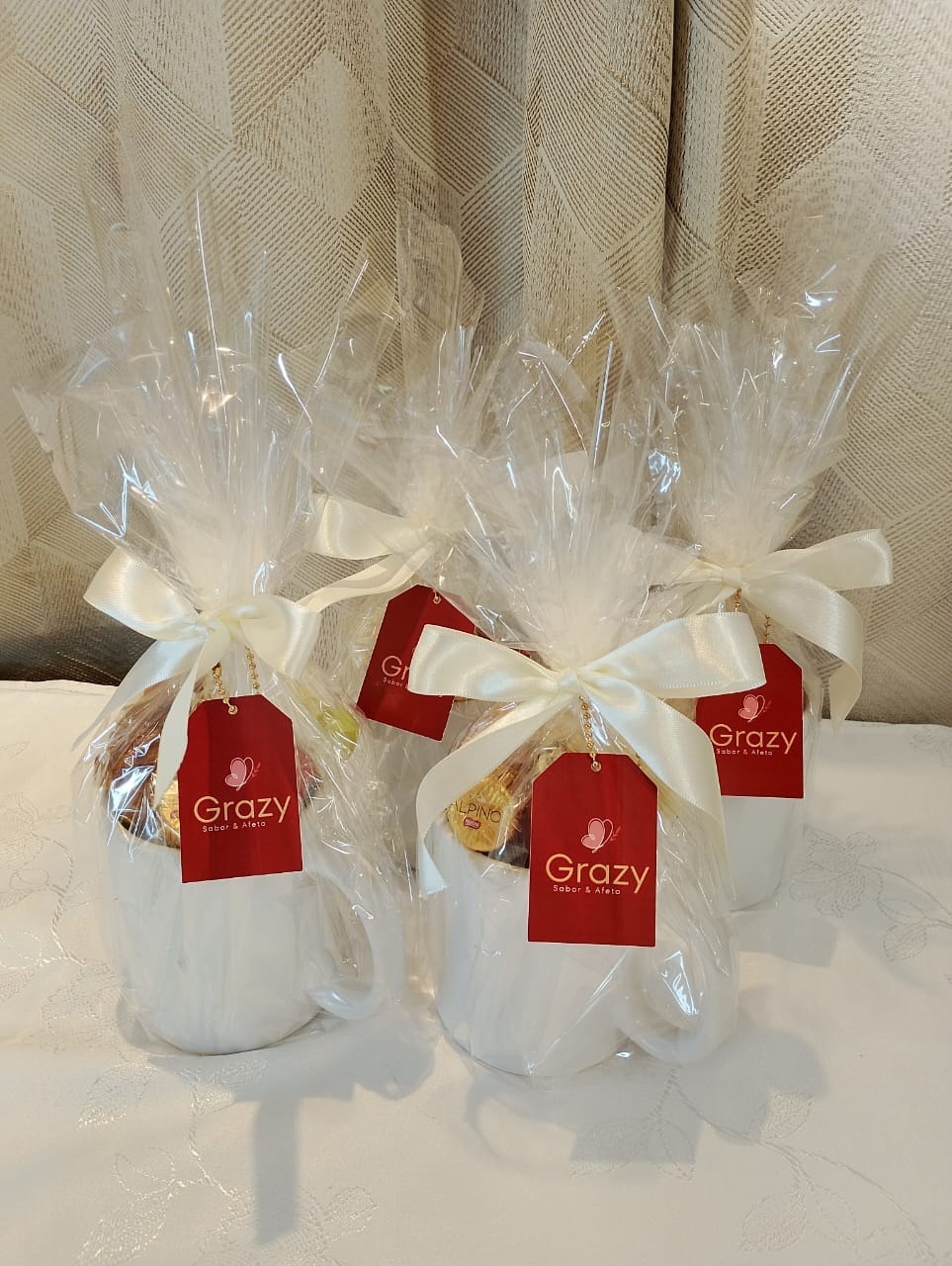 Canecas embrulhadas em celofane com laço creme e tag Grazy